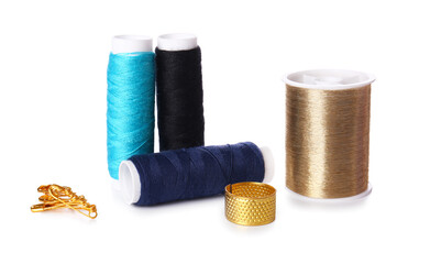 Different thread spools, thimble and safety pins on white background
