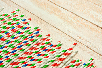 Stylish straws for drinks on light wooden background