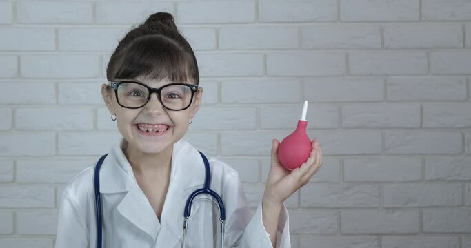 Work with enema. A working doctor child hold an enema in her hands in the room. A little girl plays a doctor.