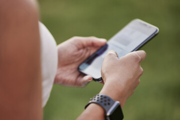 Monitoring her progress on a new fitness app. Closeup shot of an unrecognisable woman using a cellphone while exercising outdoors.