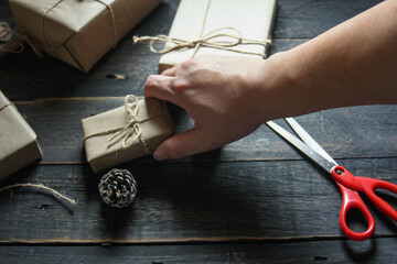 Obraz na płótnie Canvas gift wrapping from Kraft paper wrapped with twine, the concept of handmade, placed on black wooden table