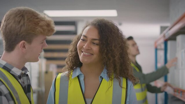 Female team leader in distribution warehouse training male intern- shot in slow motion