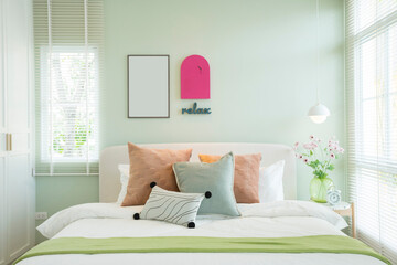 Modern bedroom with green and pink pillows on bed. Stylish bedroom interior design.