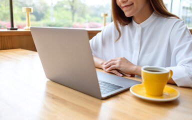 Closeup image of a young woman using and working on laptop computer