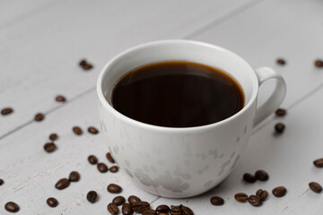 white cup of coffee close-up with scattered grains