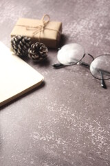 Blank Notebook, Pen, Glasses and small gift boxes placed on a gray table.