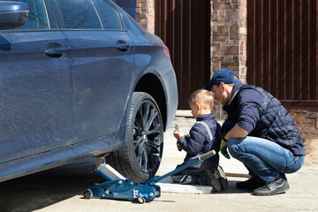 Fototapeta na wymiar Father and son are fixing the car. The son helps the dad. Happy Father's Day.