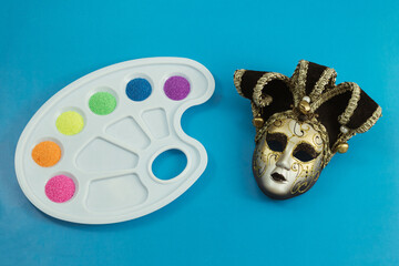 Multicolored sand, poured into the cells of the artist's palette, and a Venetian theatrical mask....