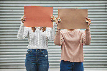 Raise your voice. Cropped shot of two unrecognizable women holding signs while taking part in a...