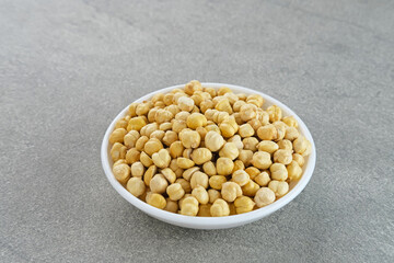 Chickpeas in white bowl on grey background. Space for text.
