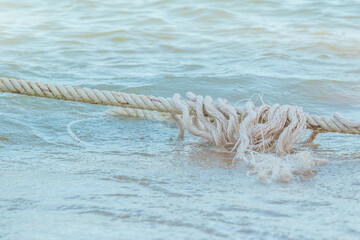 Tear white robe on the sea water with wave. robe between anchor and boat at he beach.