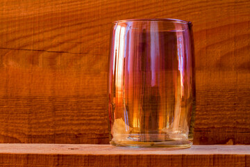 An empty glass against a background of wood.