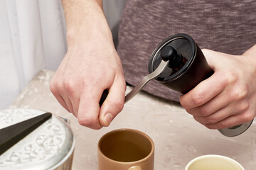Fototapeta na wymiar a man makes coffee in a geyser grinds coffee in a coffee grinder
