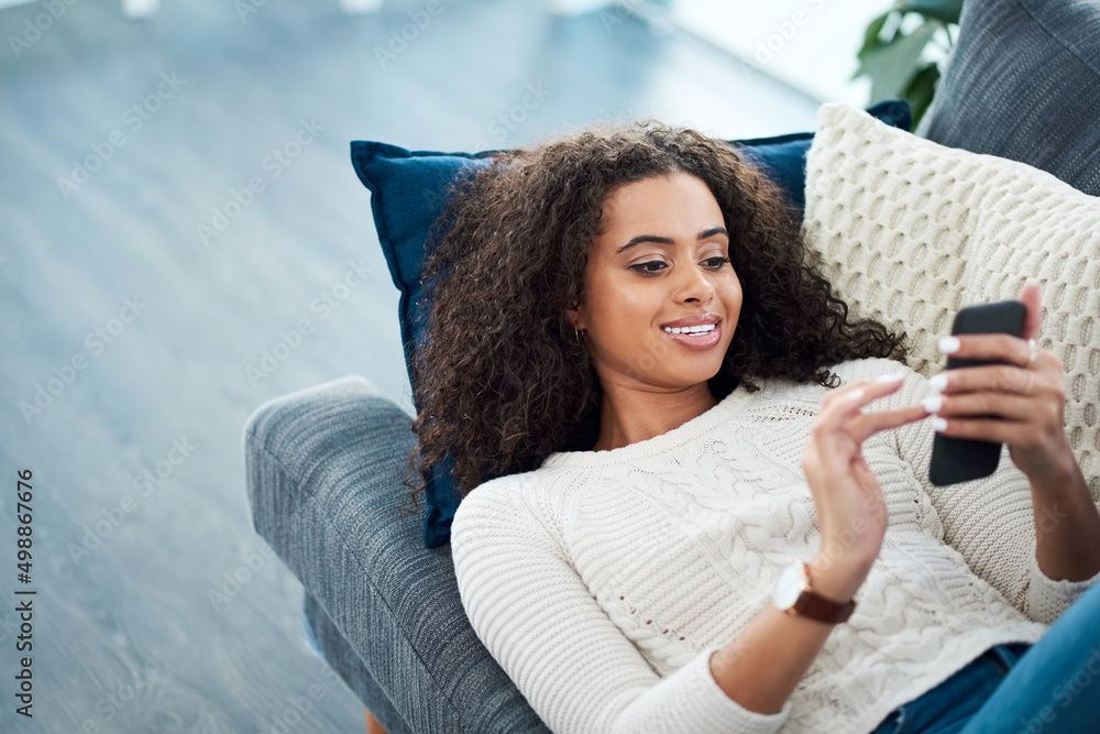 Poster connecting with old and new friends. shot of a young woman using her cellphone while relaxing at hom