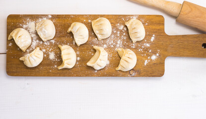 Handmade dumplings on a wooden board, top view