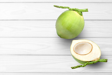 Fresh green coconut fruit with water drops and cut in half sliced isolated on white wooden table...