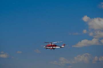Fototapeta na wymiar Firefighter red-white helicopter on a blue background. Italian helicopter flight on blue sky.