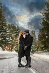 couple kissing against the backdrop of a snow-covered mountain forest and a highway