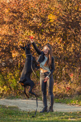 girl plays with a Doberman dog with a ball