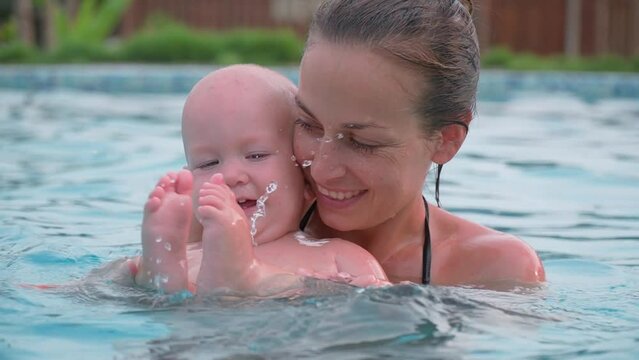 Mom plays with the baby in the pool. Healthy lifestyle.