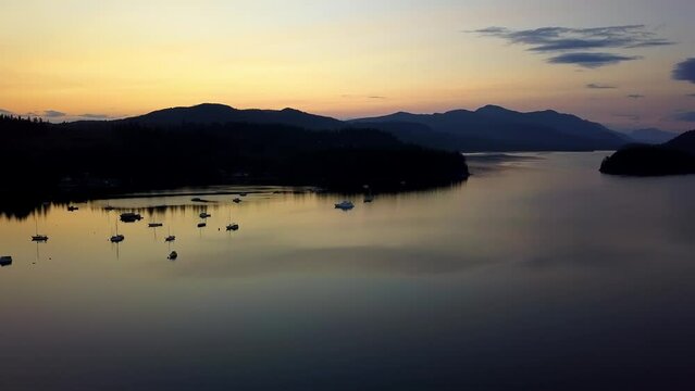 Silhouette of Mountains and Boats Against an Orange Sky During Sunset in Sechelt Inlet British Columbia, Canada - Ascending Pedestal Shot