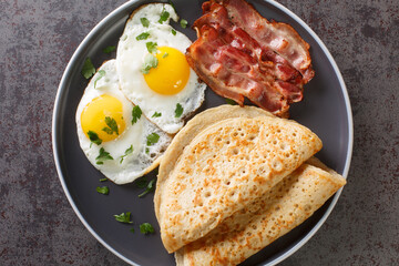Delicious oatcakes served with egg and bacon close-up in a plate on the table. horizontal top view from above