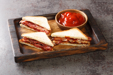 English Bacon Sandwich closeup in the wooden tray on the table. Horizontal