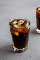 Cold Refreshing Dark Cola with Ice Cubes on a gray background, low angle view. Close-up.