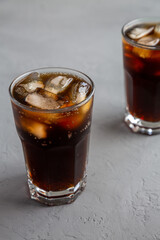 Cold Refreshing Dark Cola with Ice Cubes on a gray background, side view. Close-up.