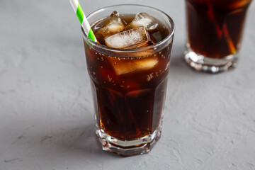 Cold Refreshing Dark Cola with Ice Cubes on a gray background, low angle view.