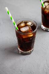 Cold Refreshing Dark Cola with Ice Cubes on a gray background, side view.