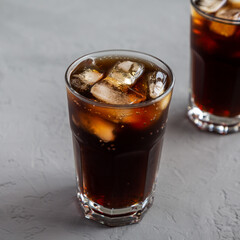 Cold Refreshing Dark Cola with Ice Cubes on a gray background, low angle view.