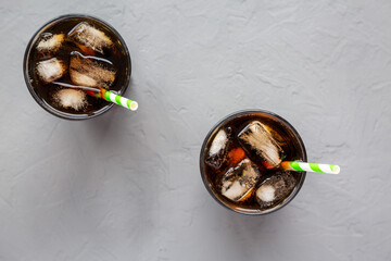 Cold Refreshing Dark Cola with Ice Cubes, Straws on a gray background, top view. Flat lay,...