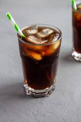 Cold Refreshing Dark Cola with Ice Cubes, Straws on a gray background, side view.