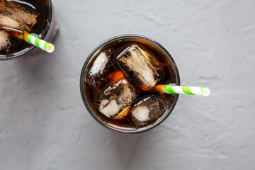 Cold Refreshing Dark Cola with Ice Cubes, Straws on a gray surface, top view. Flat lay, overhead,...