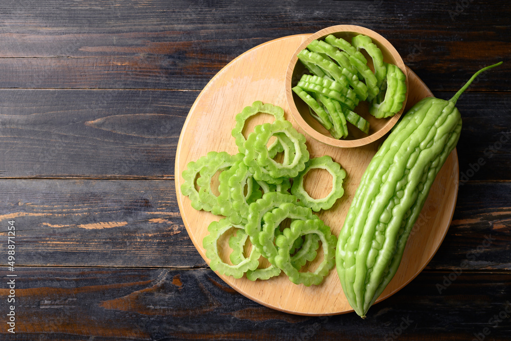 Wall mural Sliced bitter melon or bitter gourd on wooden board prepare for cooking, Table top view