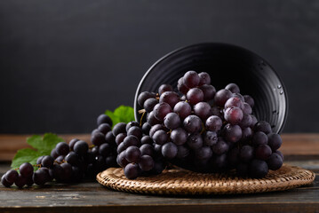 Red grape in bowl on wooden with black background