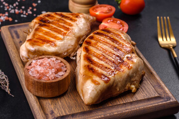 Delicious fresh grilled chicken fillet with spices and herbs on a dark concrete background