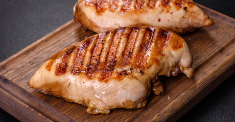 Delicious fresh grilled chicken fillet with spices and herbs on a dark concrete background
