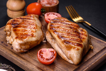 Delicious fresh grilled chicken fillet with spices and herbs on a dark concrete background