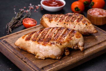 Delicious fresh grilled chicken fillet with spices and herbs on a dark concrete background