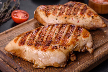 Delicious fresh grilled chicken fillet with spices and herbs on a dark concrete background