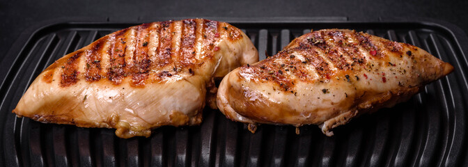 Delicious fresh grilled chicken fillet with spices and herbs on a dark concrete background