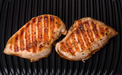 Delicious fresh grilled chicken fillet with spices and herbs on a dark concrete background