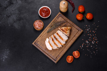 Delicious fresh grilled chicken fillet with spices and herbs on a dark concrete background