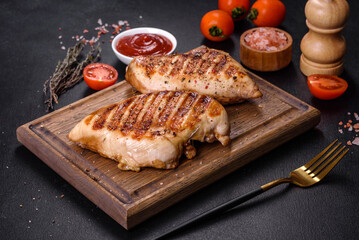 Delicious fresh grilled chicken fillet with spices and herbs on a dark concrete background
