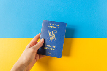 Woman's hand hold Ukraine biometric passport on the national flag of Ukraine. Blue and yellow...