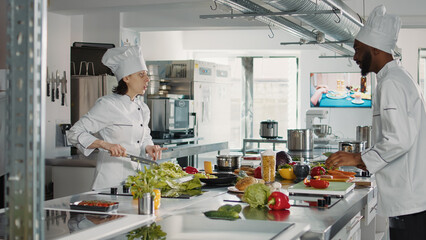 Fototapeta na wymiar Man and woman cutting fresh ingredients to make gourmet dish, doing teamwork to prepare vegetables for gastronomic meal. Professional chefs in uniform cooking organic food in kitchen cuisine.