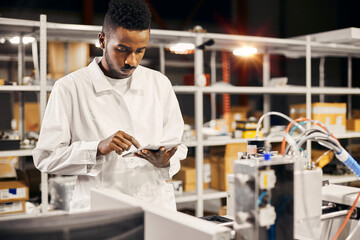 African engineer programming equipment with tablet at factory