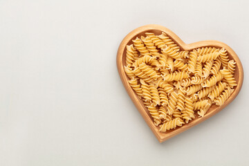 Pasta in a heart shaped wood bowl.